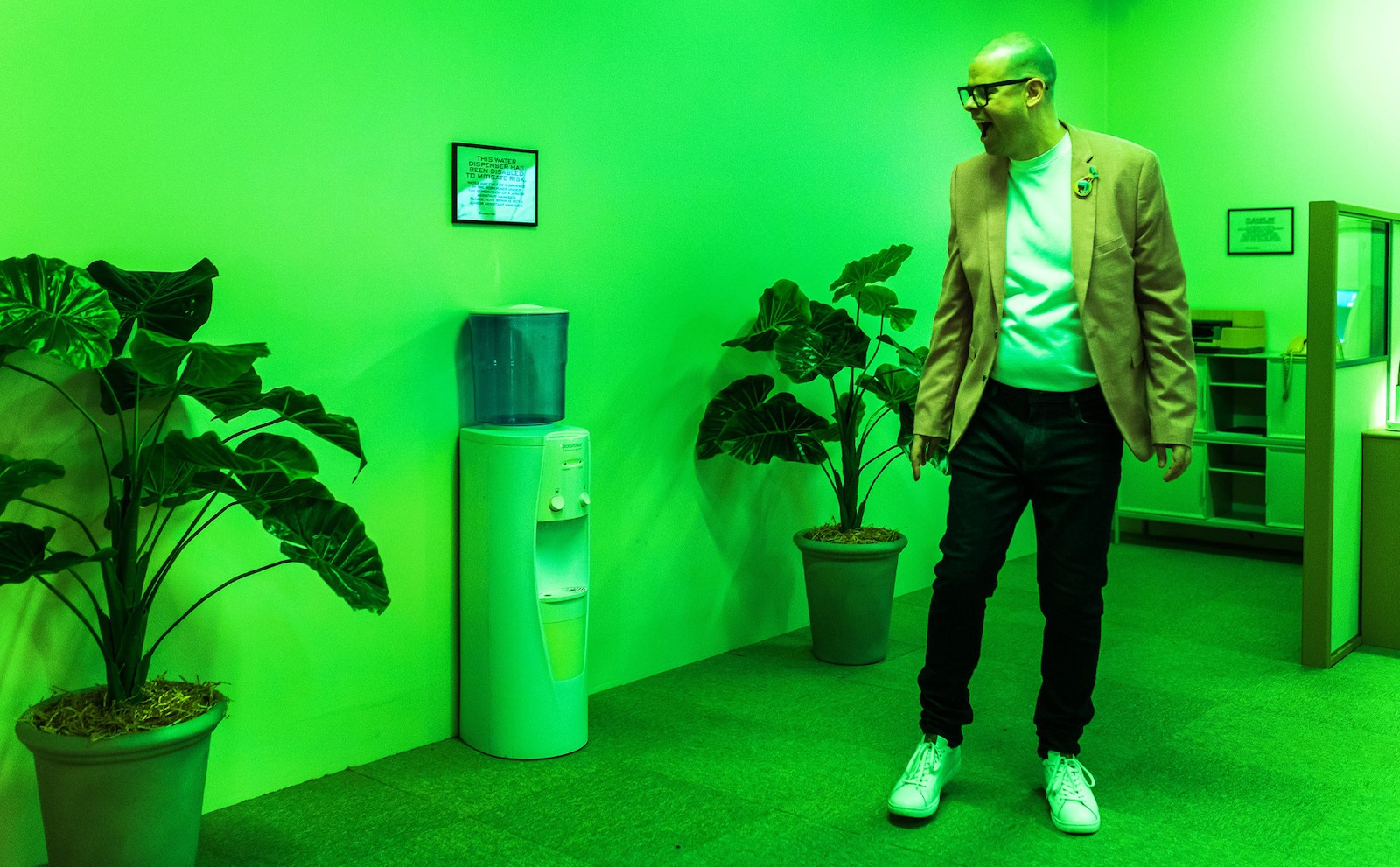 A man stands within a makeshift corporate office bathed in green light