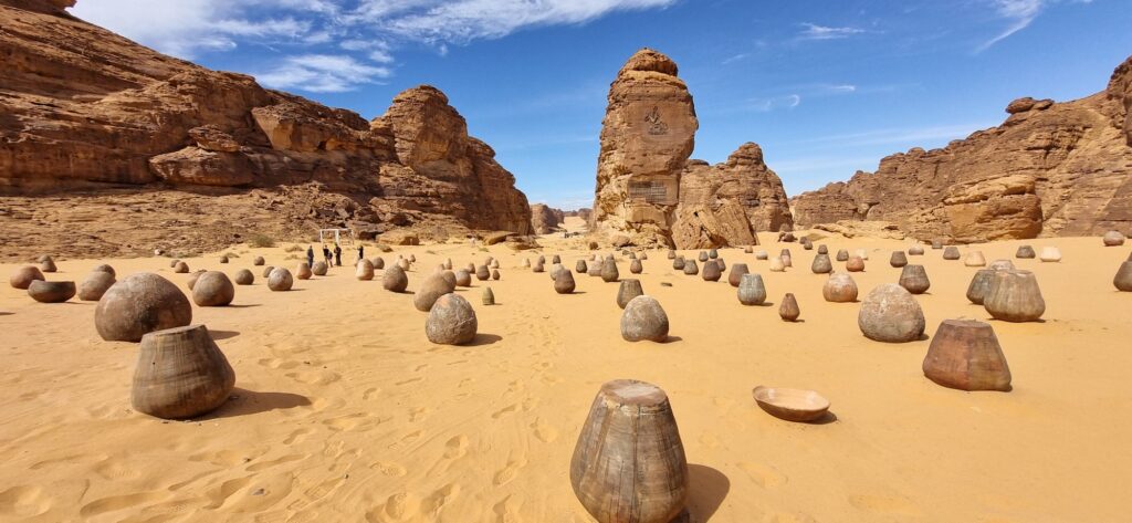 Large, upturned sandy-coloured vessels are potted across a desert floor
