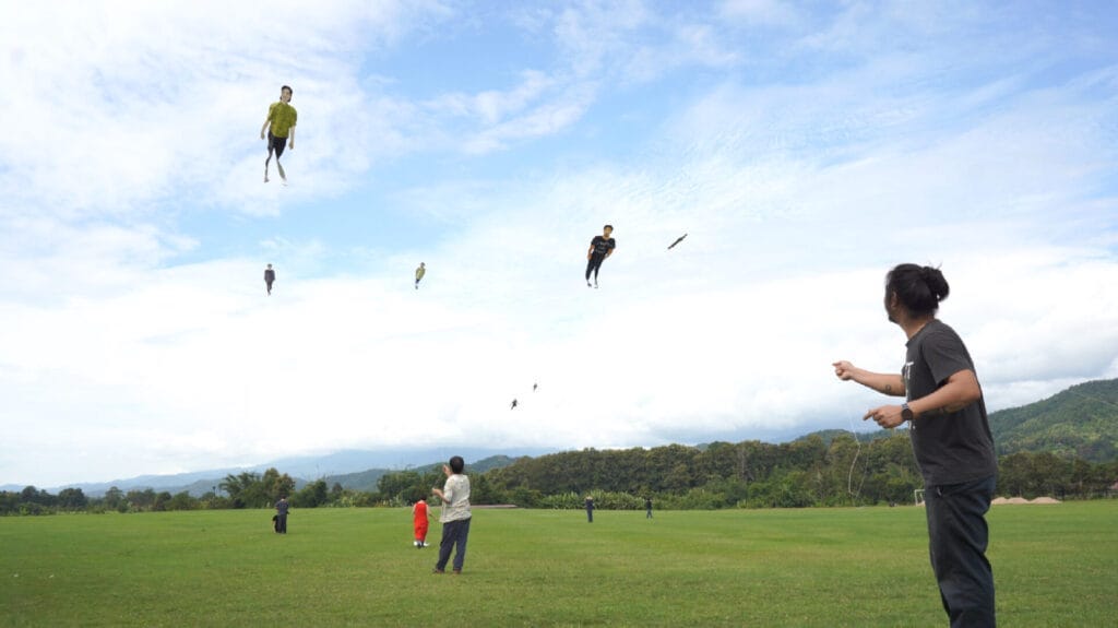 People stand in a park flying kites of life-size human figures.