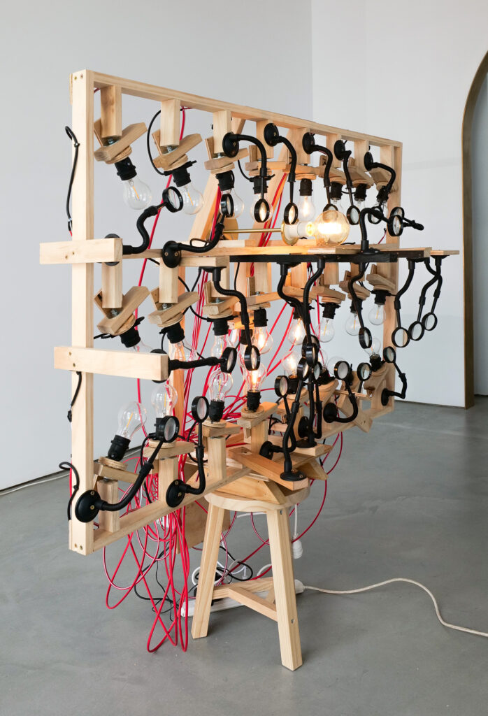 Multiple exposed light bulbs and magnifying glasses are arranged in three vertical rows on a wooden scaffold.	