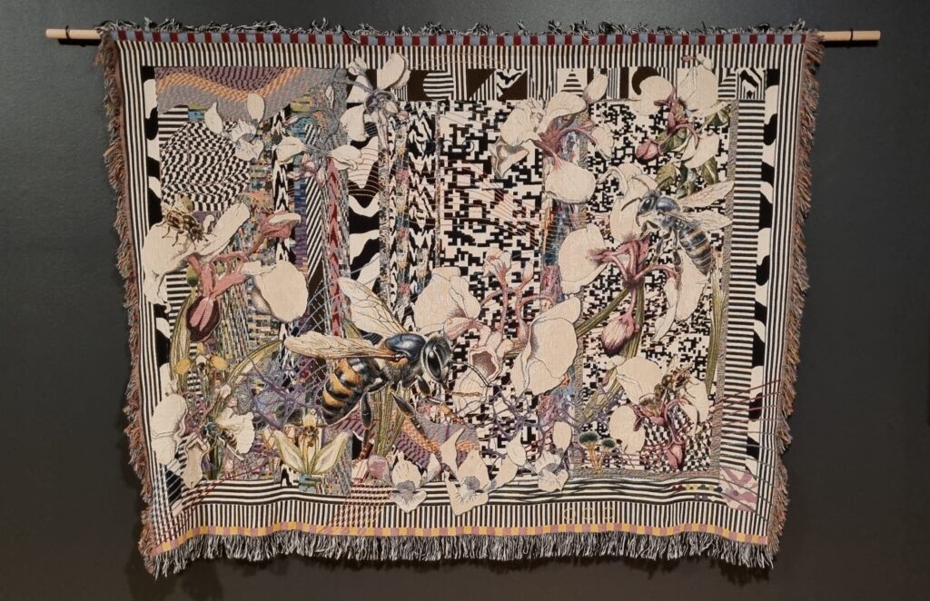 A large tapestry depicts bees, flowers and abstract black and white patterns.