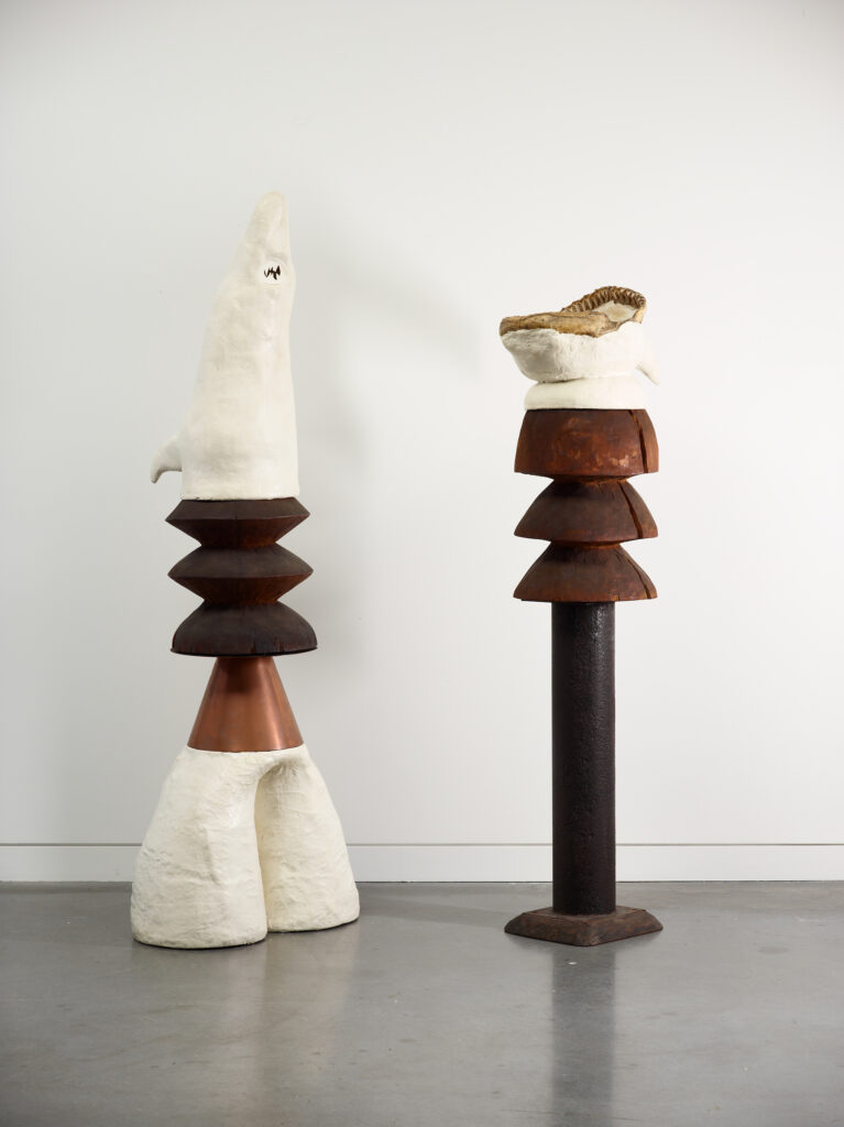 Two Modernist and totemic like sculptures of sharks standing on end.