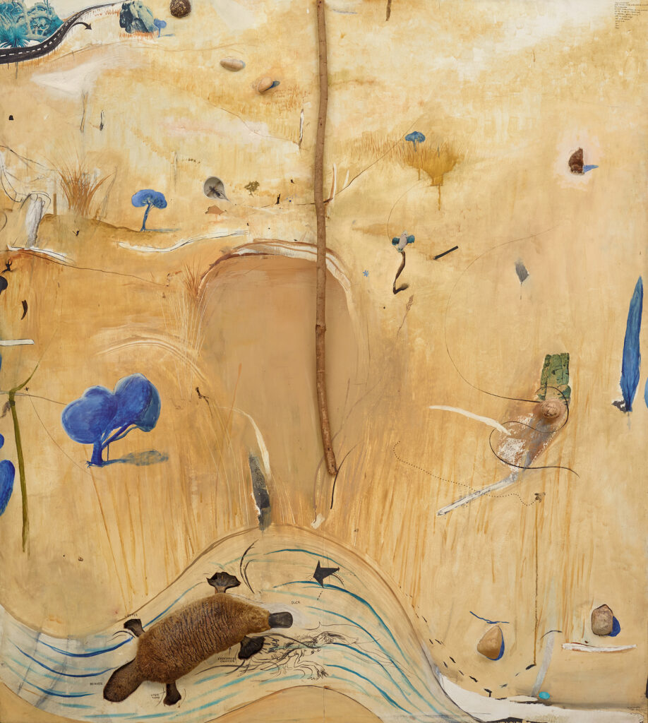 An Australian landscape painting in a warm sand colour with objects, including a platypus, stick and shells, collaged to its surface.