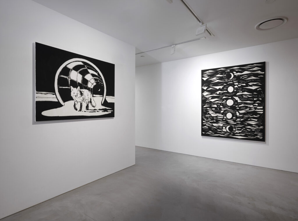 Two black and white paintings on perpendicular walls depict a fox within a futuristic scene and an abstract series of circles and mountainesque landscapes.