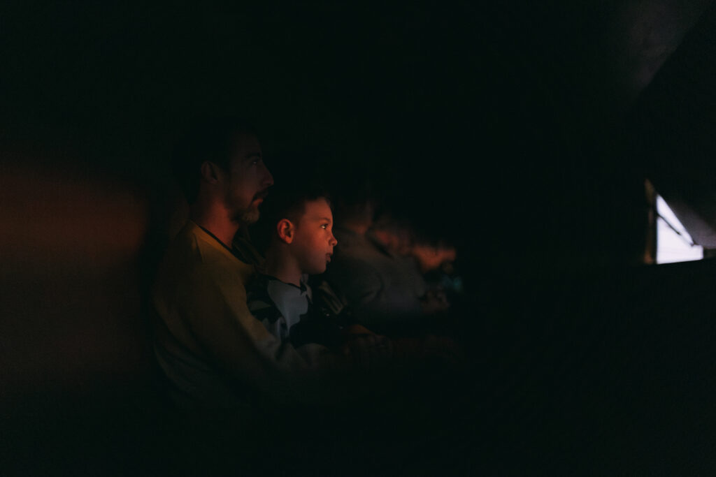 A photograph of a child and an adult surrounded in darkness, soft light illuminates their faces.