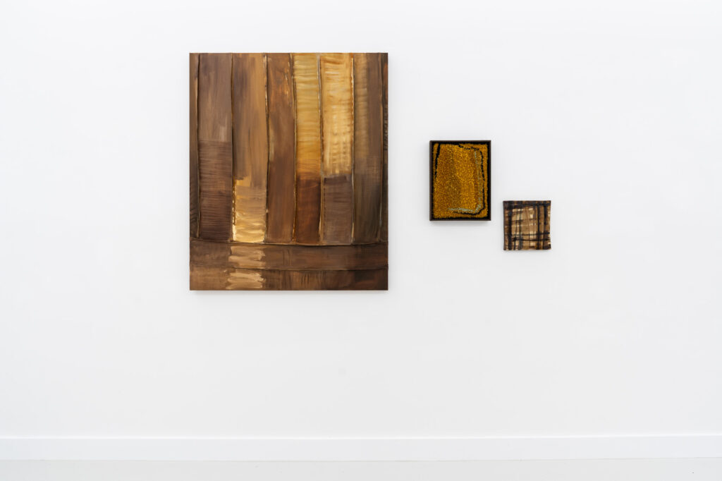 Three abstract works in browns hang on a white gallery wall