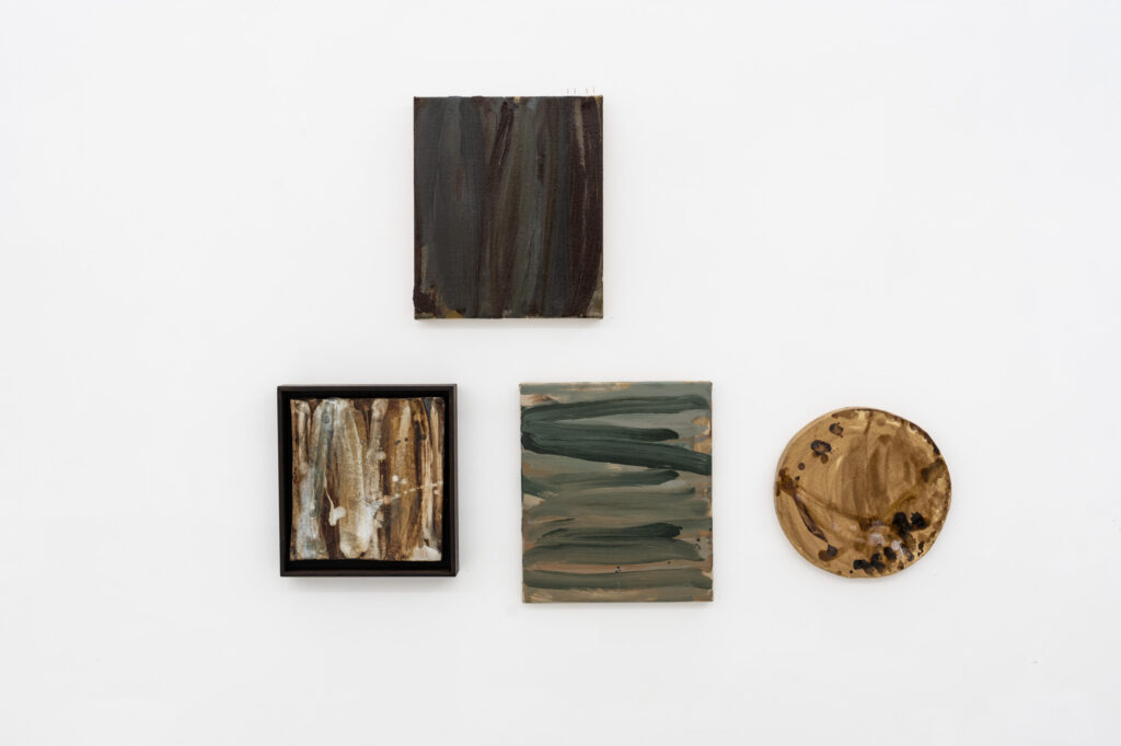 Four abstract works in browns hang on a white gallery wall