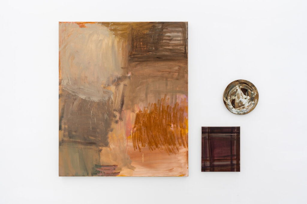 Three abstract works in browns hang on a white gallery wall