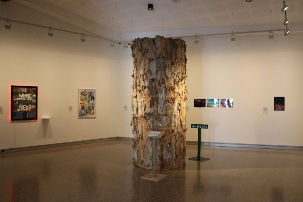 A constructed tree made of mixed media and natural materials, hollowed out and housing a projector and speaker system. 