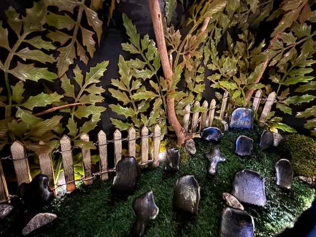 A photograph shows a small dark cemetery garden made of natural and manmade objects.