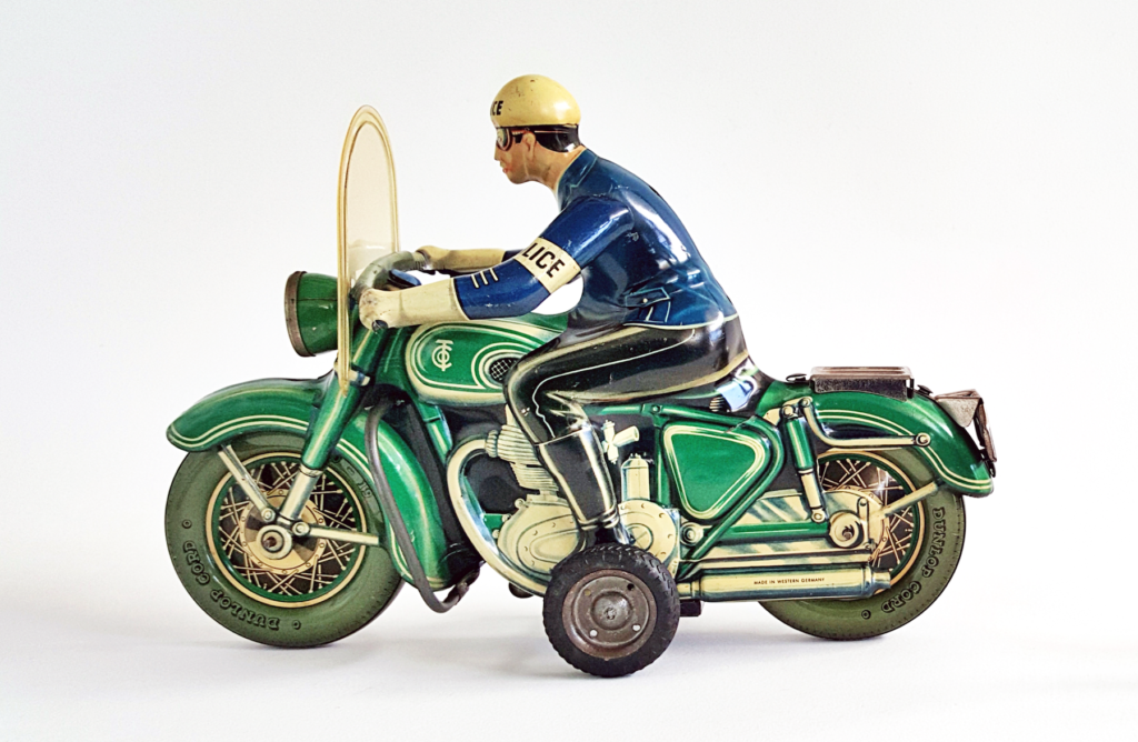 A photograph of an 1950s mechanical toy – a policeman in blue on a green motorbike.