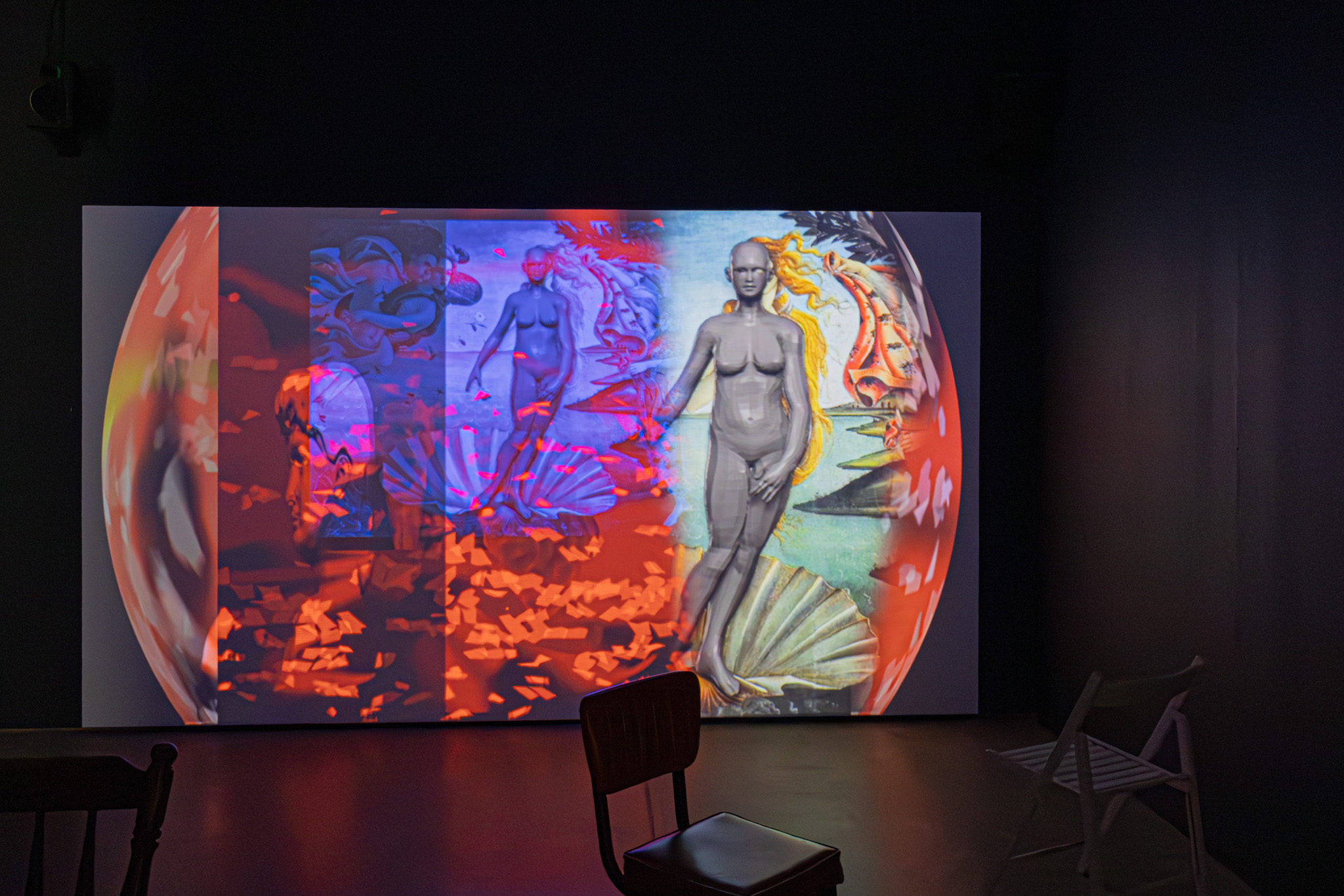 a large screen in a dark room plays a colourful video work remixing Botticelli fragments with digital imagery.