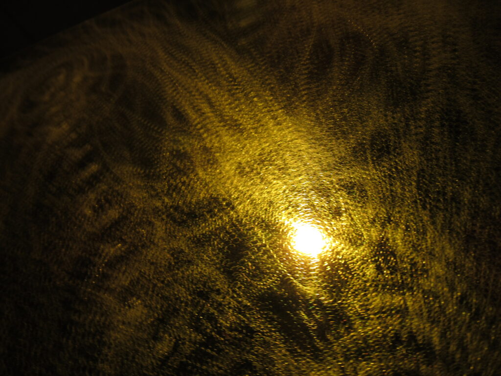 Close up image of the angle grinder scuffs on the surface of the yellow acrylic.