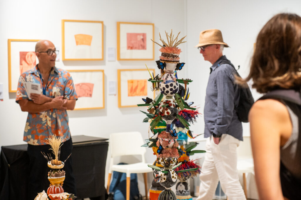 People move through a booth featuring a colourful sculptural work.
