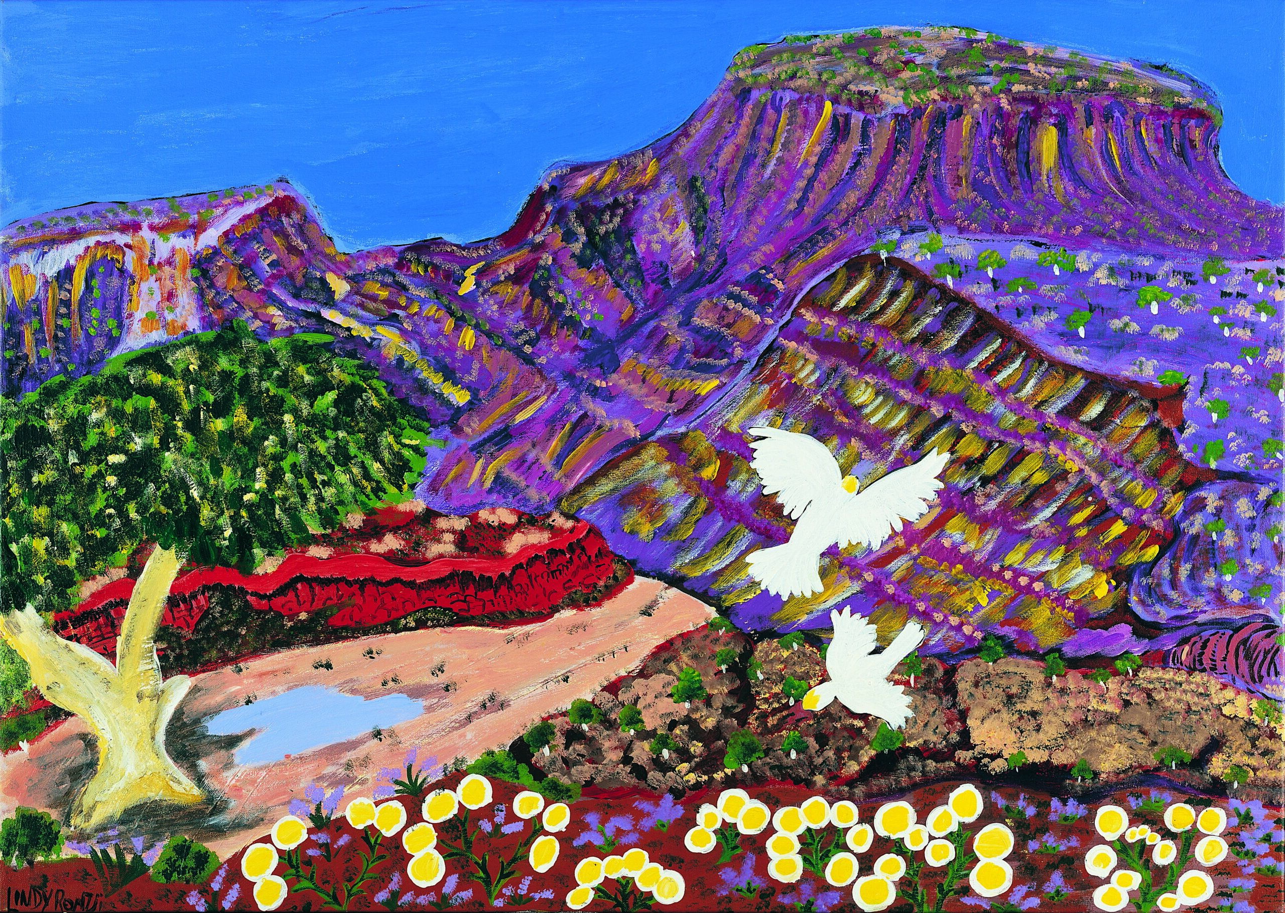 A scene shows white crested cockatoos flying over purple mountains a valley containing a tree and a small body of water.