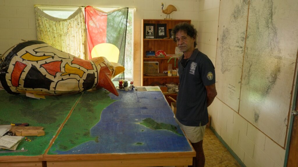 Leonard Andy stand before a map of the local area laid modelled into a table.
