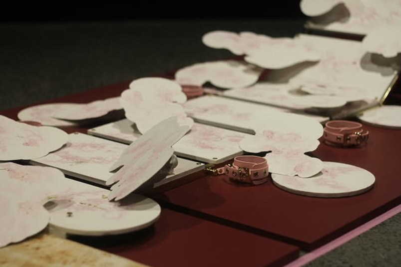 a burgundy platform is topped with white and pink plaster forms set flat and on angles
