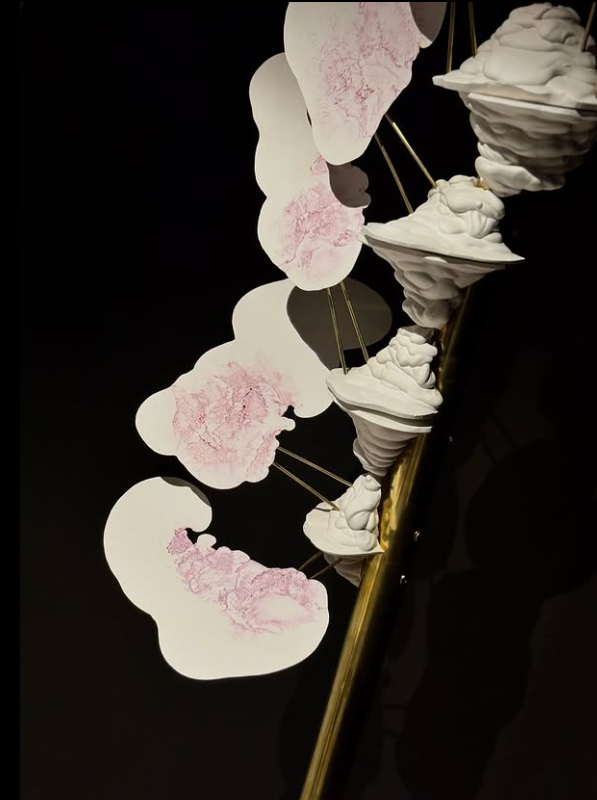 a brass pole with white and pink plaster forms protruding from it
