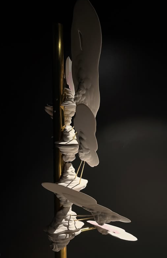 a brass pole with white and pink plaster forms protruding from it